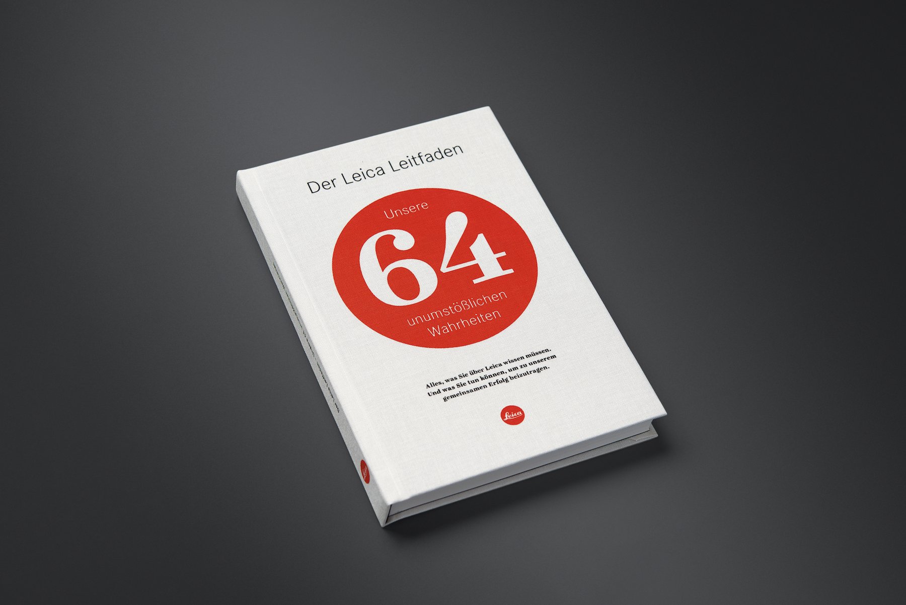 Weißes Buch „Der Leica Leitfaden“ mit roter 64